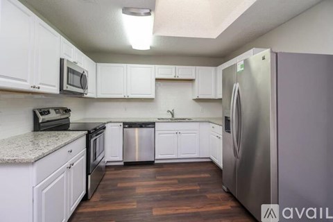 A kitchen with white cabinets and a stainless steel refrigerator.
