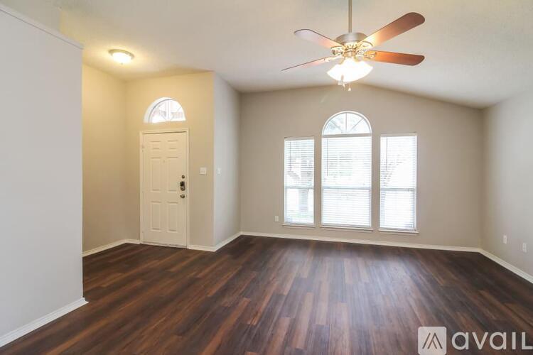 A room with a ceiling fan and wooden flooring.