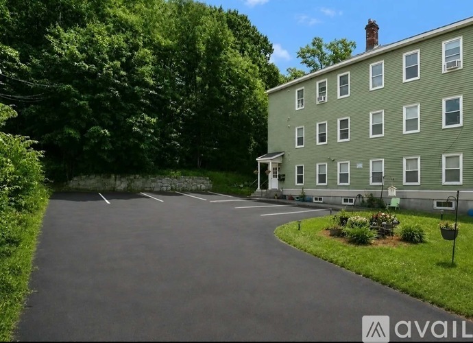 A large green building with a driveway in front of it.