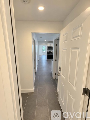 A hallway with a white door and tiled floor.