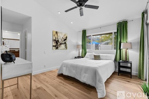 A bedroom with a white bed and a ceiling fan.