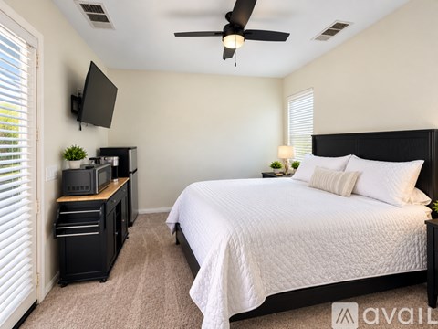 A bedroom with a bed, a television, and a ceiling fan.