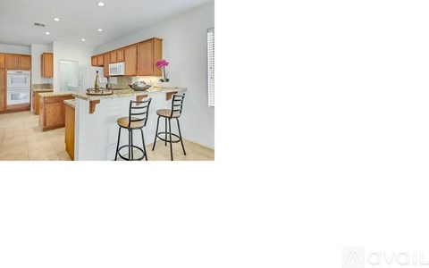 A kitchen with wooden cabinets and a bar area with two stools.