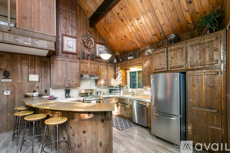 A kitchen with wooden walls and a stainless steel refrigerator.