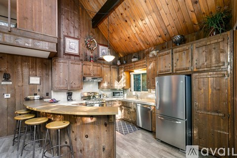A kitchen with wooden walls and a stainless steel refrigerator.