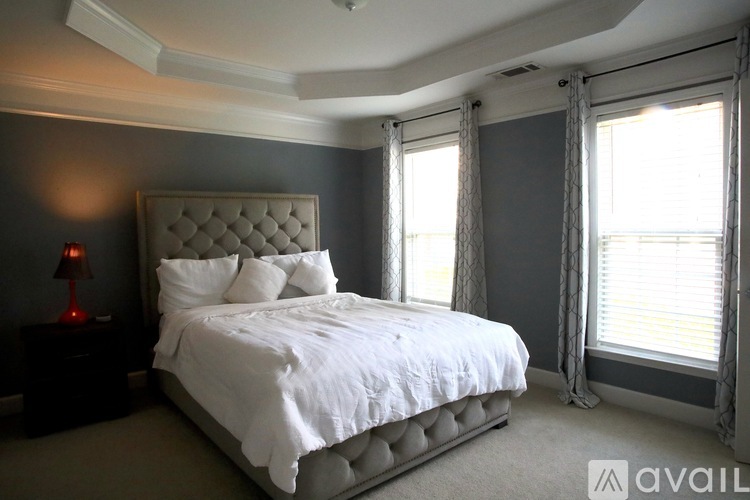 A bedroom with a large bed and a window with curtains.