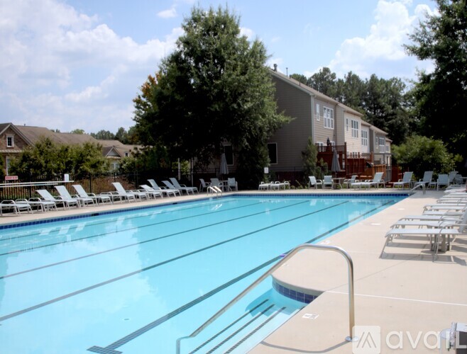 A large swimming pool with lounge chairs and trees in the background.