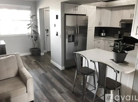 A kitchen with a refrigerator, stove, and table.