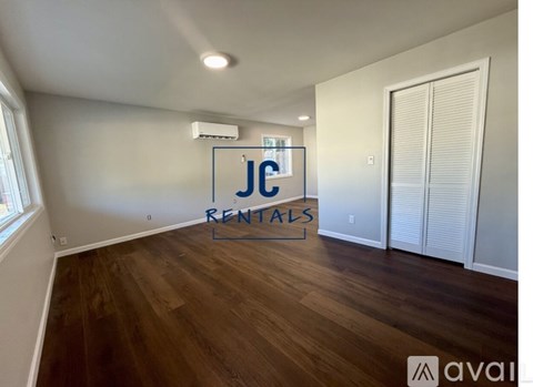 A room with wooden flooring and a sign that says "JC RENTALS" is available for rent.