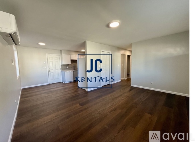 A room with wooden flooring and a sign that says "JC RENTALS" is available for rent.