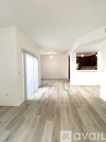 A spacious room with wooden flooring and a large window.