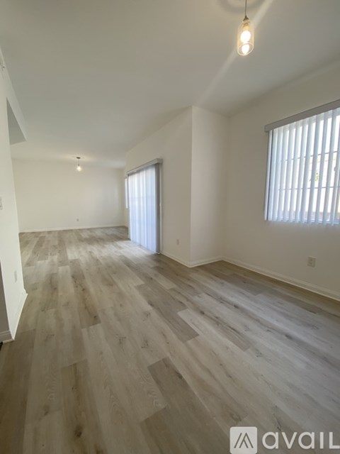 A room with wooden flooring and a window with blinds.