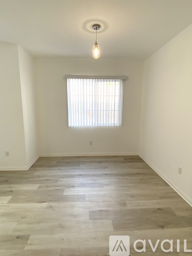 A room with wooden flooring and a window with blinds.