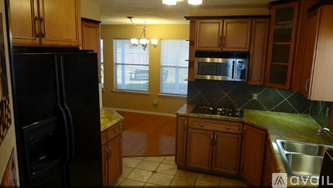 A kitchen with wooden cabinets and a black refrigerator.