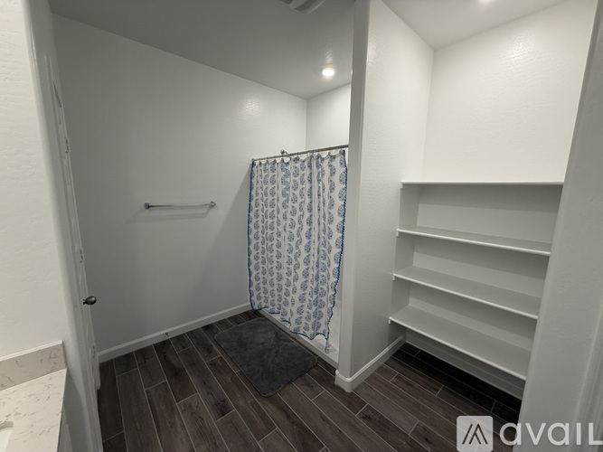 A small bathroom with a shower curtain and a wooden floor.