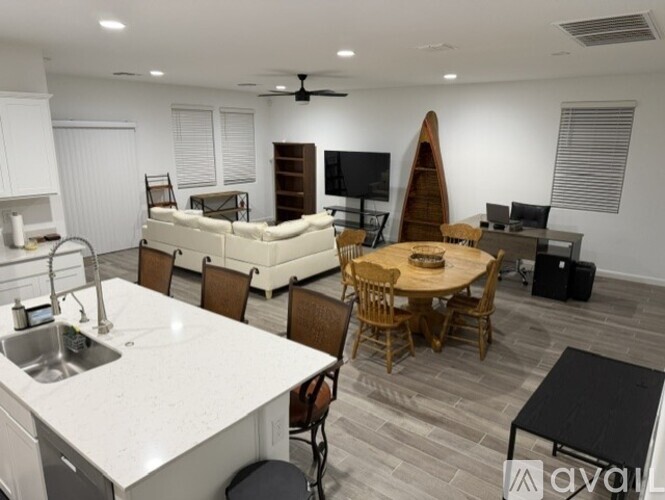 A modern kitchen with a dining table and chairs, a sofa, and a TV.