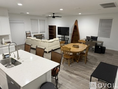 A modern kitchen with a dining table and chairs, a sofa, and a TV.