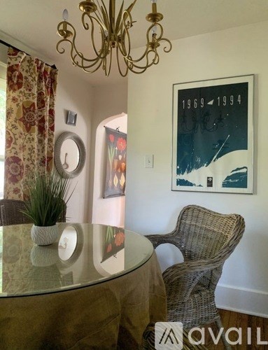 A dining room with a glass table and a wicker chair.