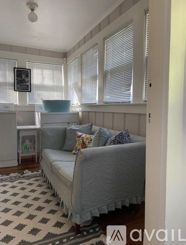 A living room with a grey couch and a black and white checkered rug.