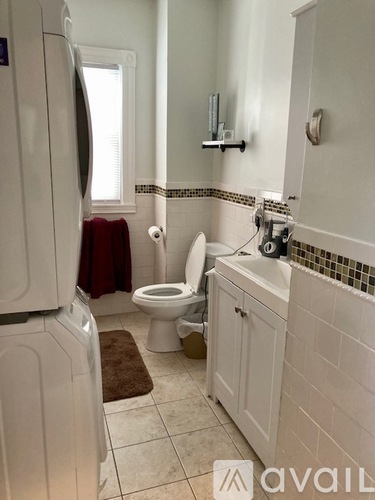 A bathroom with a toilet, sink, and a white fridge.
