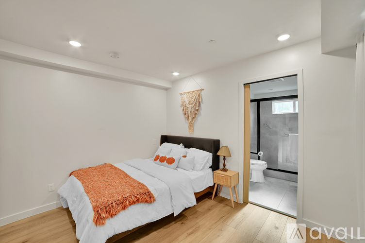 A bedroom with a bed, nightstand, and a window.