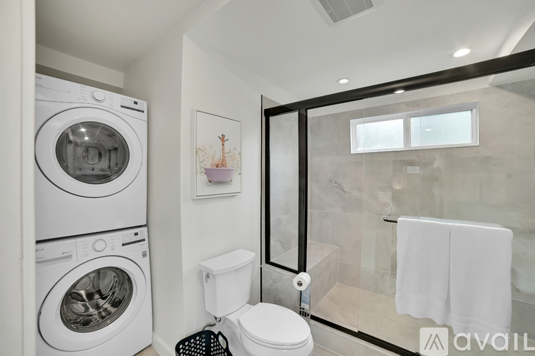 A modern bathroom with a washer and dryer built into the cabinetry.