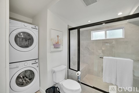 A modern bathroom with a washer and dryer built into the cabinetry.