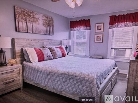 A bedroom with a bed, nightstand, and a painting on the wall.