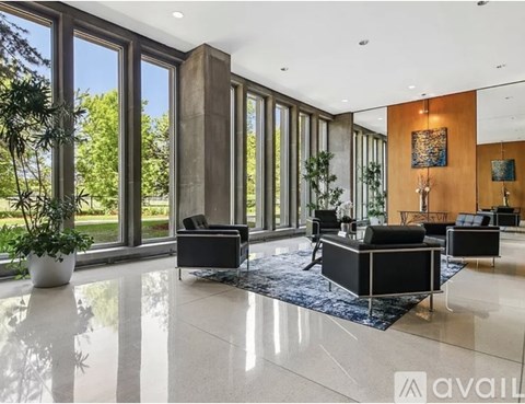 A spacious living room with a large window and a plant.