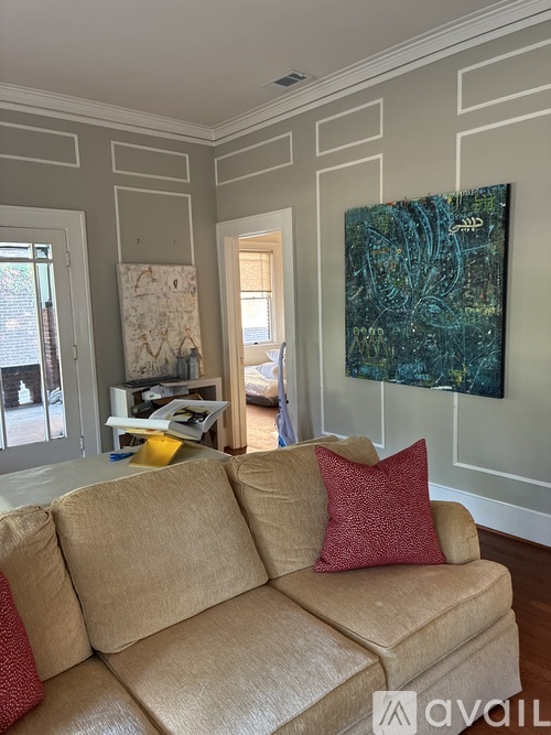 A living room with a beige couch and a painting on the wall.