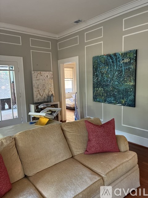 A living room with a beige couch and a painting on the wall.