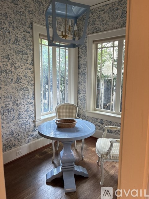 A blue table with a bowl on it sits in front of a window.