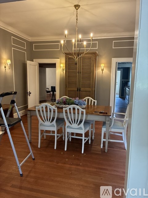 A dining room with a wooden table and white chairs.