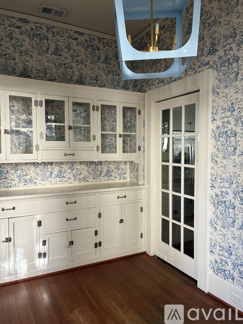 A kitchen with white cabinets and a blue floral wallpaper.
