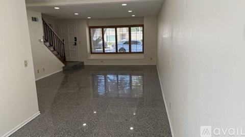 A spacious room with a staircase and a window.