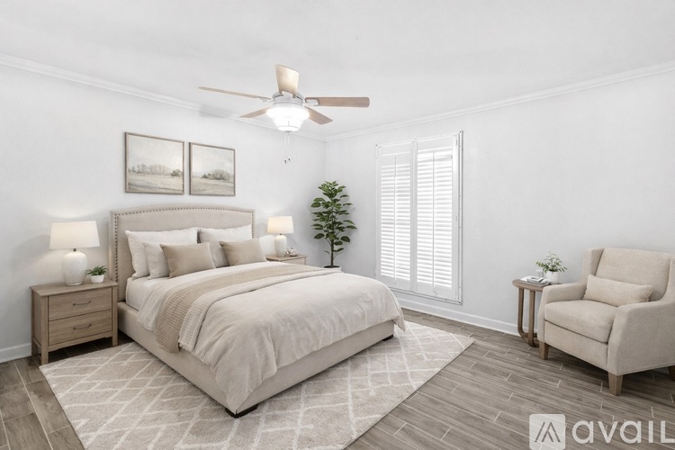 A well-lit bedroom with a large bed, a chair, and a small tree.