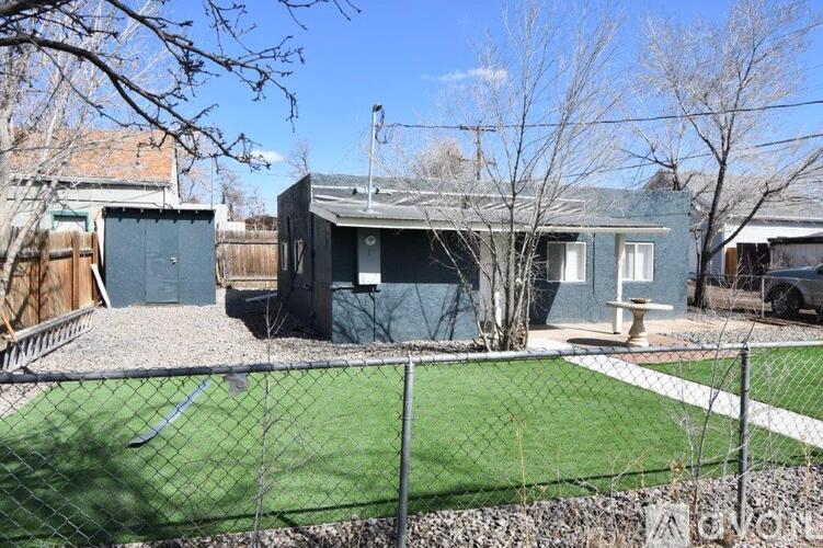 A backyard with a fence and a small building.