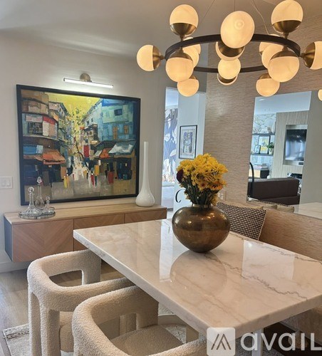 A dining room with a marble table and a painting on the wall.