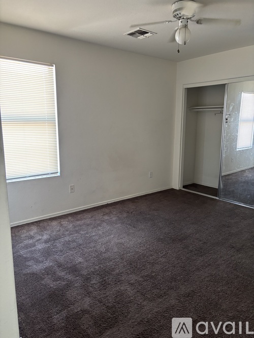 A room with a carpeted floor and a ceiling fan.