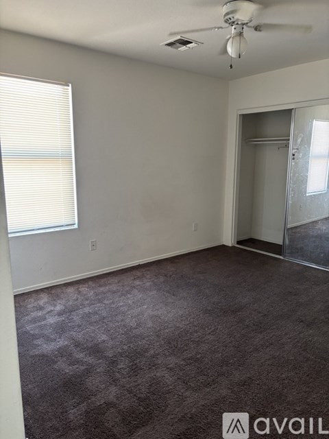 A room with a carpeted floor and a ceiling fan.