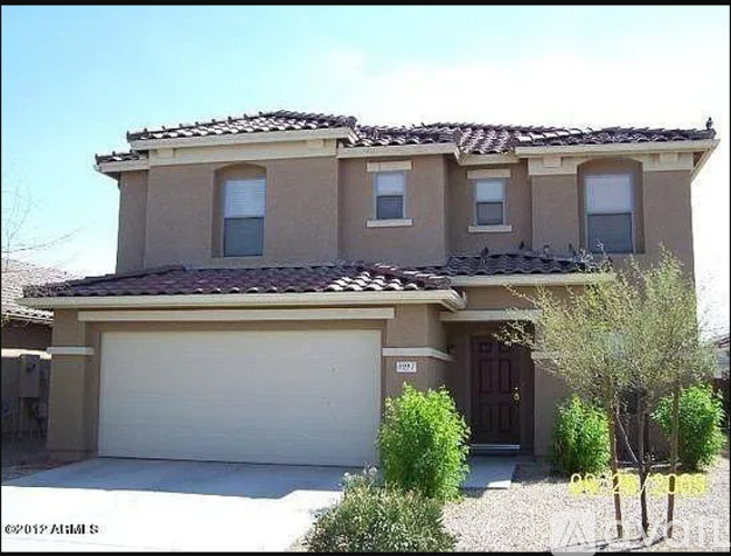 A house with a brown roof and tan walls with a white garage door.