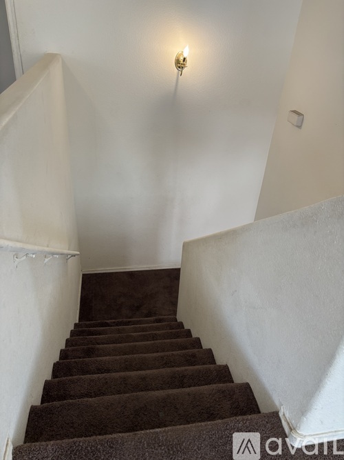 A staircase with a carpeted runner and white walls.