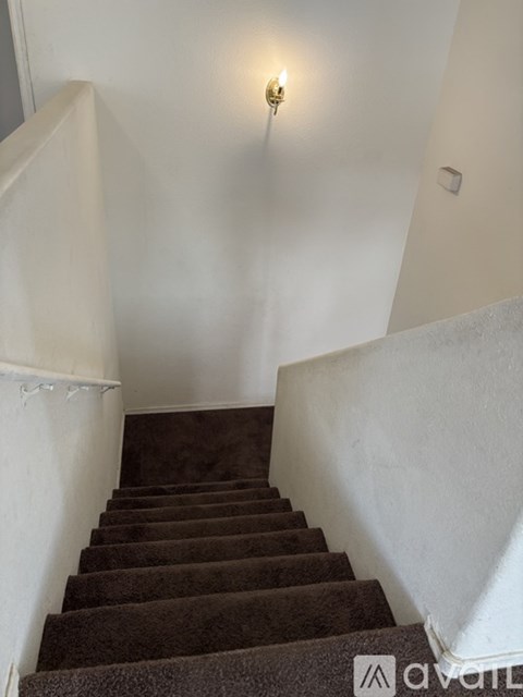 A staircase with a carpeted runner and white walls.