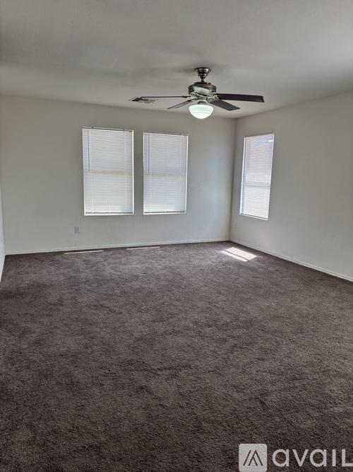 A room with a ceiling fan and carpeted floor.