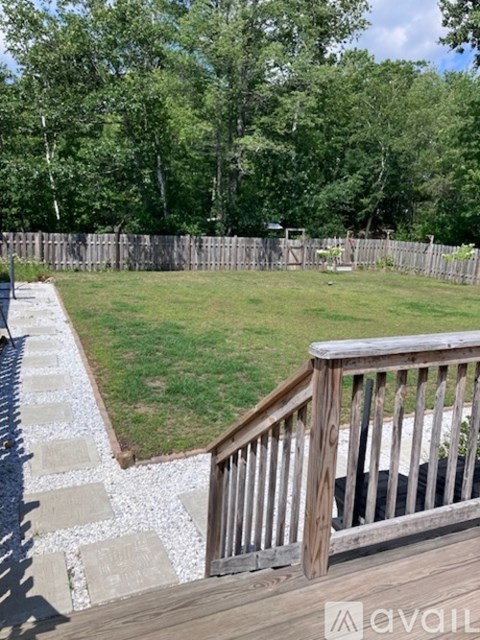 A backyard with a wooden deck and a grassy area.