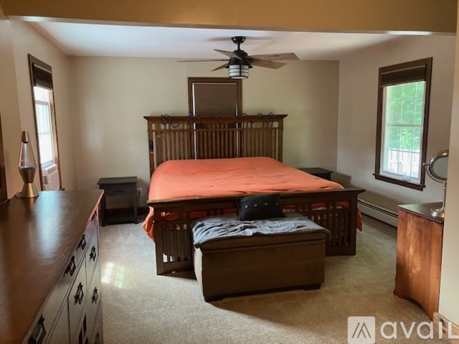 A bedroom with a bed, dresser, and ceiling fan.