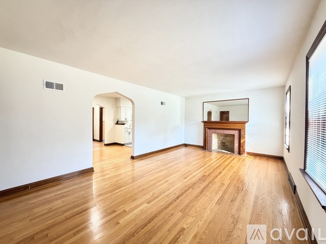 A spacious room with wooden flooring and a fireplace.