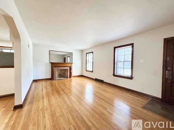 A spacious room with wooden floors and a fireplace.