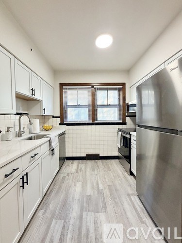 A kitchen with a stainless steel refrigerator and wooden flooring.