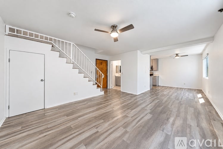 A spacious room with a staircase and wooden flooring.